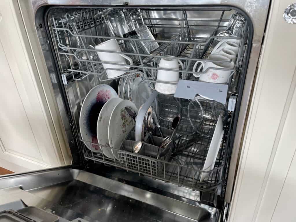 a half-full dishwasher with dirty dishes