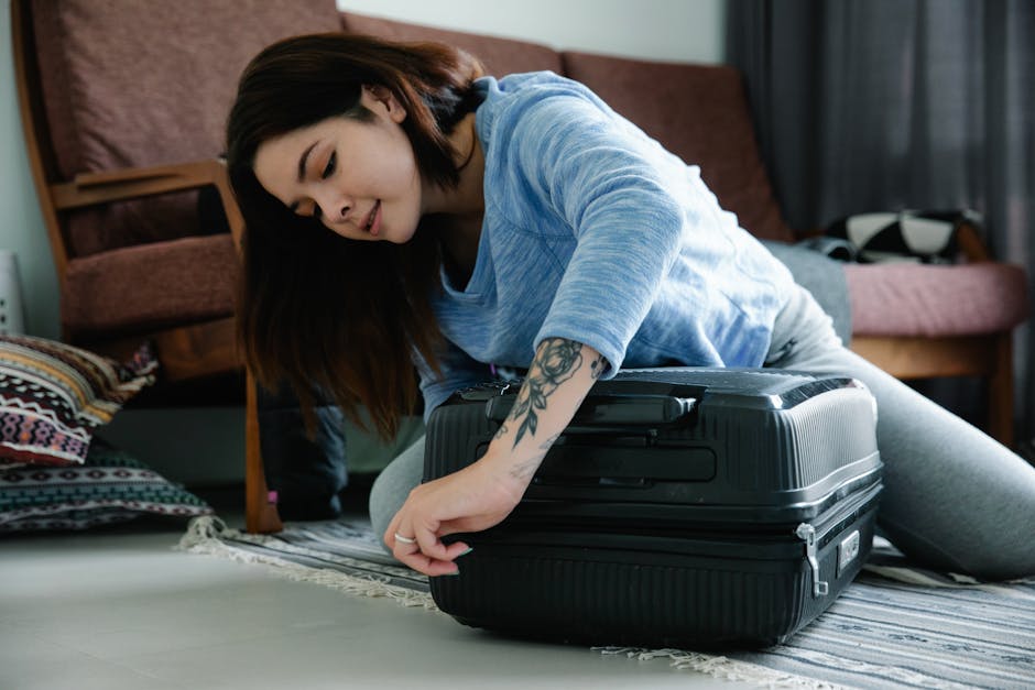 Woman kneeling on the floor struggling to close an overpacked suitcase at home before a trip