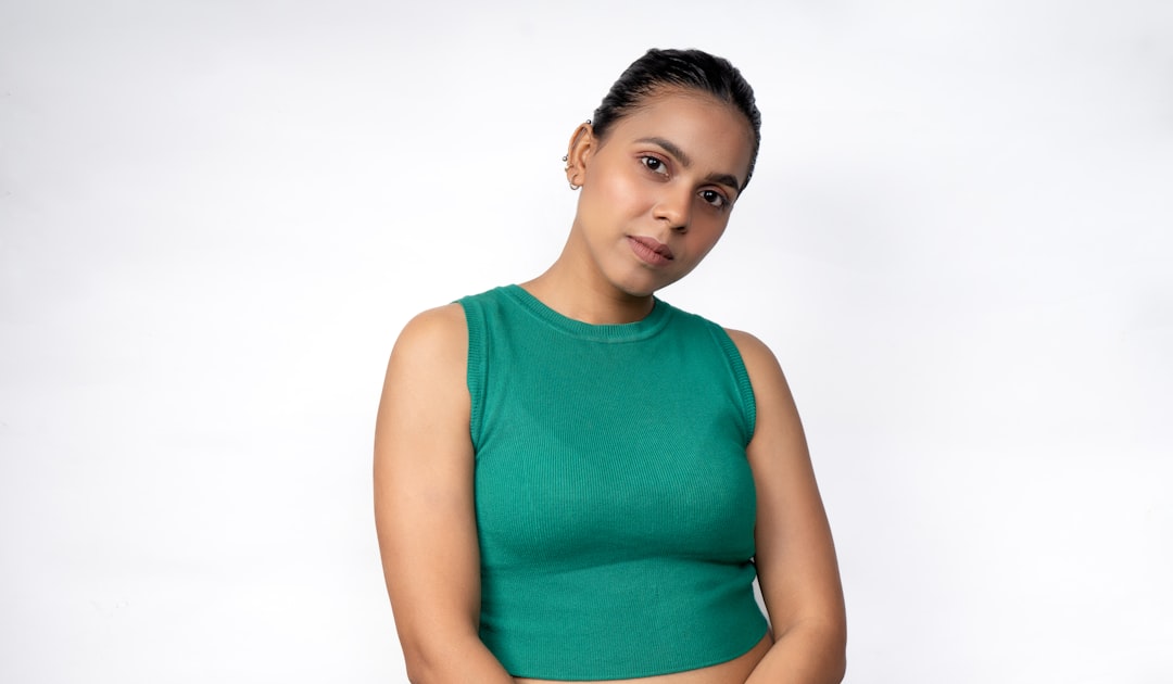 Woman wearing a fitted green ribbed top where bra lines are visible through the thin clingy fabric