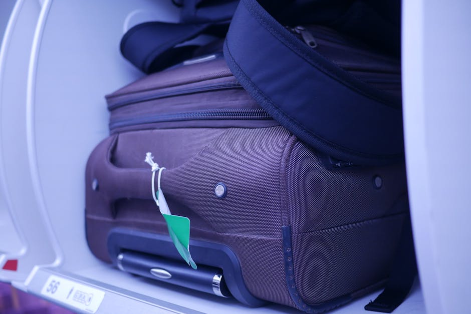 Carry-on suitcase and backpack tightly packed into airplane overhead compartment showing limited space