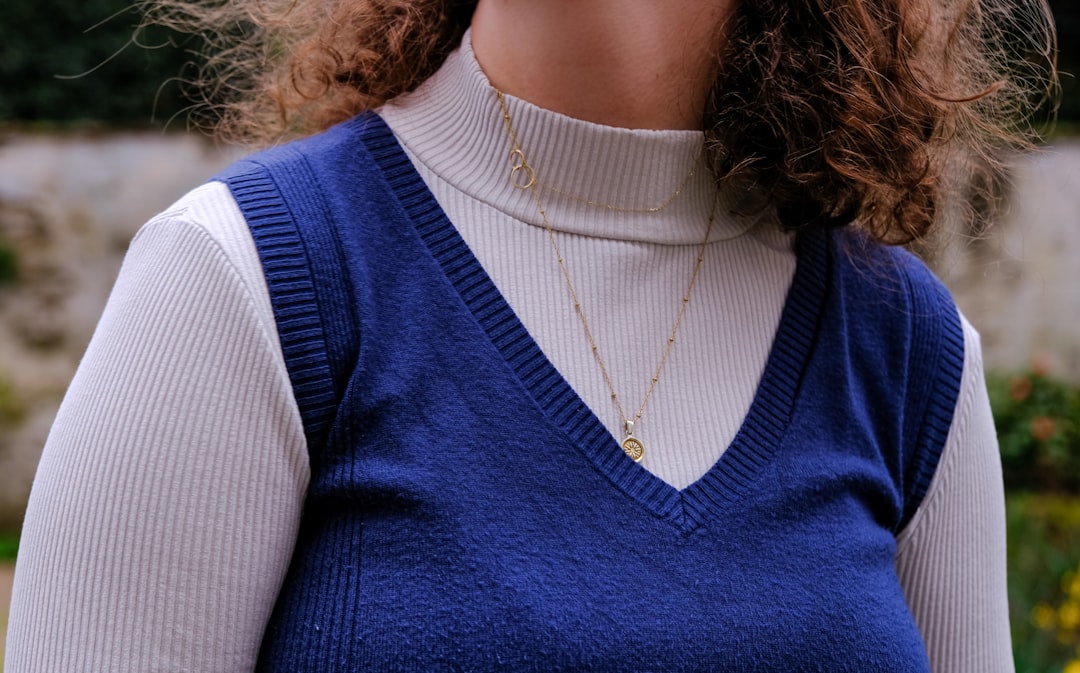 Woman wearing a white turtleneck layered under a blue V-neck sweater vest showing how layering covers cleavage