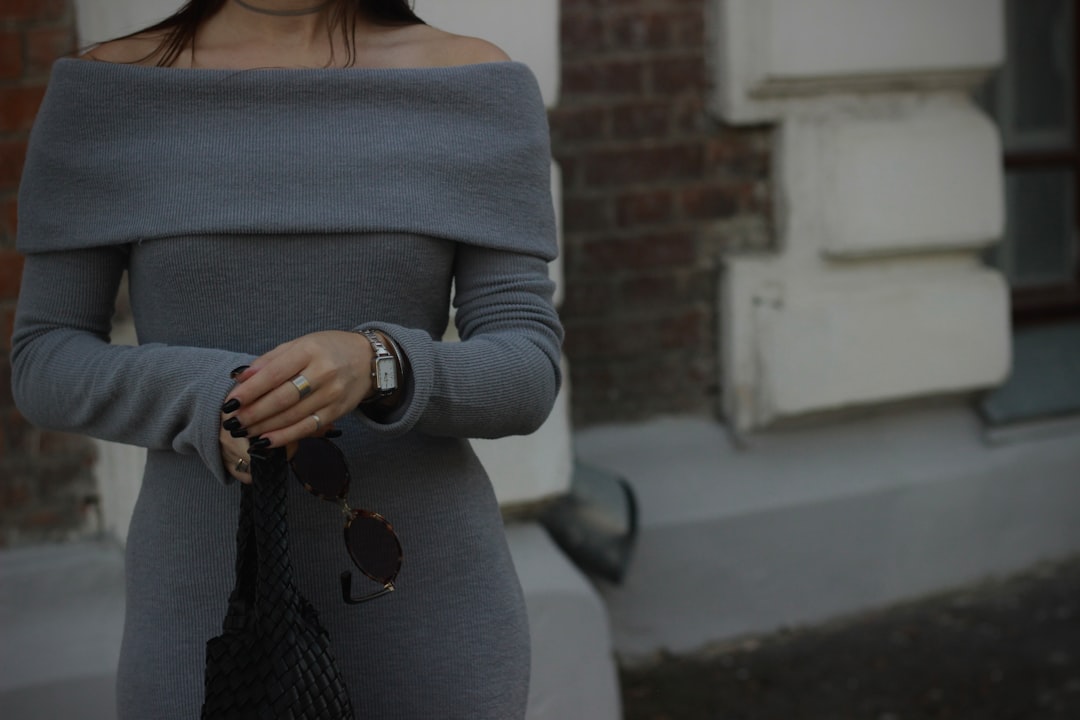 Woman wearing a grey off-shoulder dress that exposes the collarbone area, demonstrating a dressy outfit formula for showing collarbones