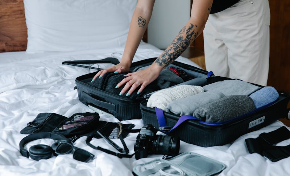 Person pressing down on neatly organized clothes inside a packing cube in a suitcase, demonstrating compression packing technique