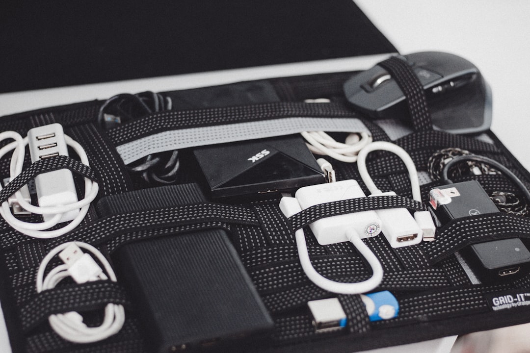 Black electronics organizer with coiled cables, mouse, power bank, and charger neatly held in place by elastic straps