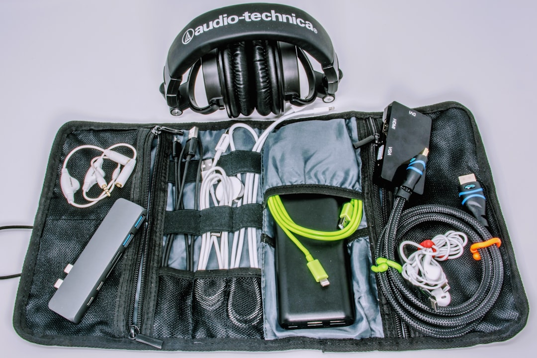 Open travel organizer pouch with charging cables, power bank, USB hub, adapters, and headphones laid out
