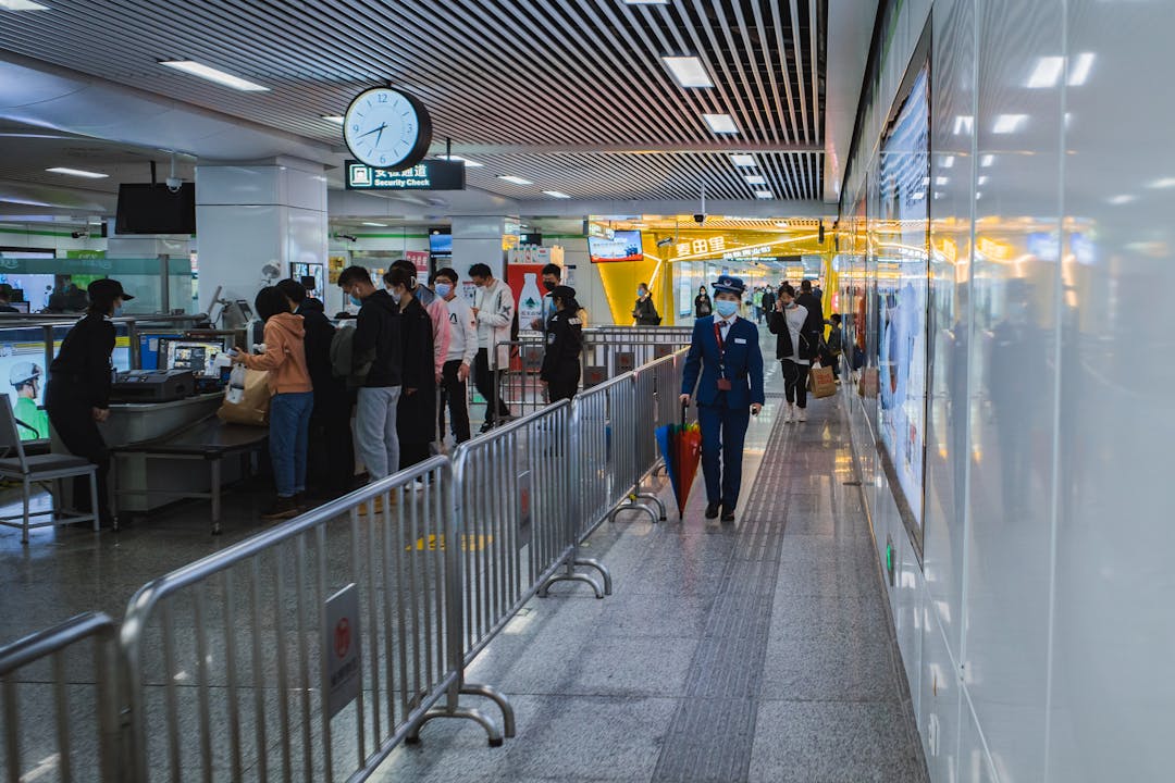 Travelers waiting in line and passing through airport security checkpoint with Security Check sign visible