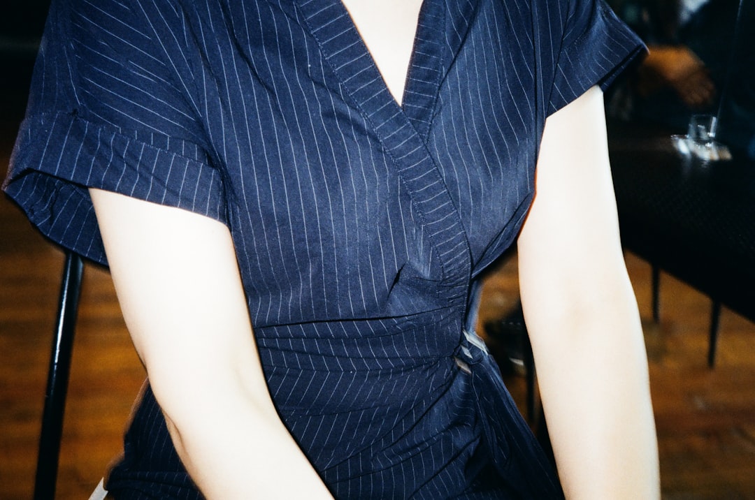 Close-up of a woman wearing a dark pinstripe wrap top that defines the waist and drapes over the hips demonstrating how wrap styles hide love handles