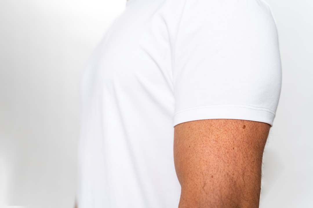 Close-up of a man in a well-fitted white t-shirt showing how proper fit follows the muscular build