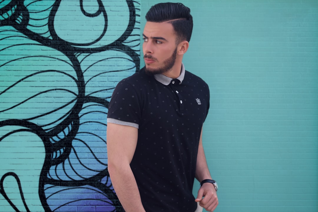 Man wearing a fitted black polo shirt that frames his biceps and shows his build, demonstrating how polo shirts work for muscular builds