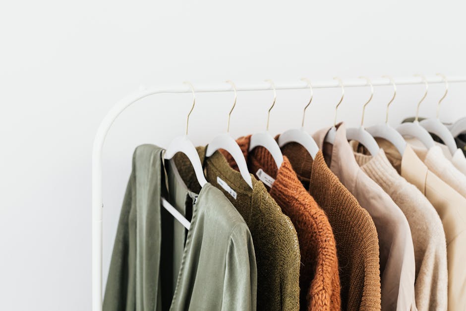 Coordinated capsule wardrobe with sweaters and shirts in neutral tones on a clothing rack
