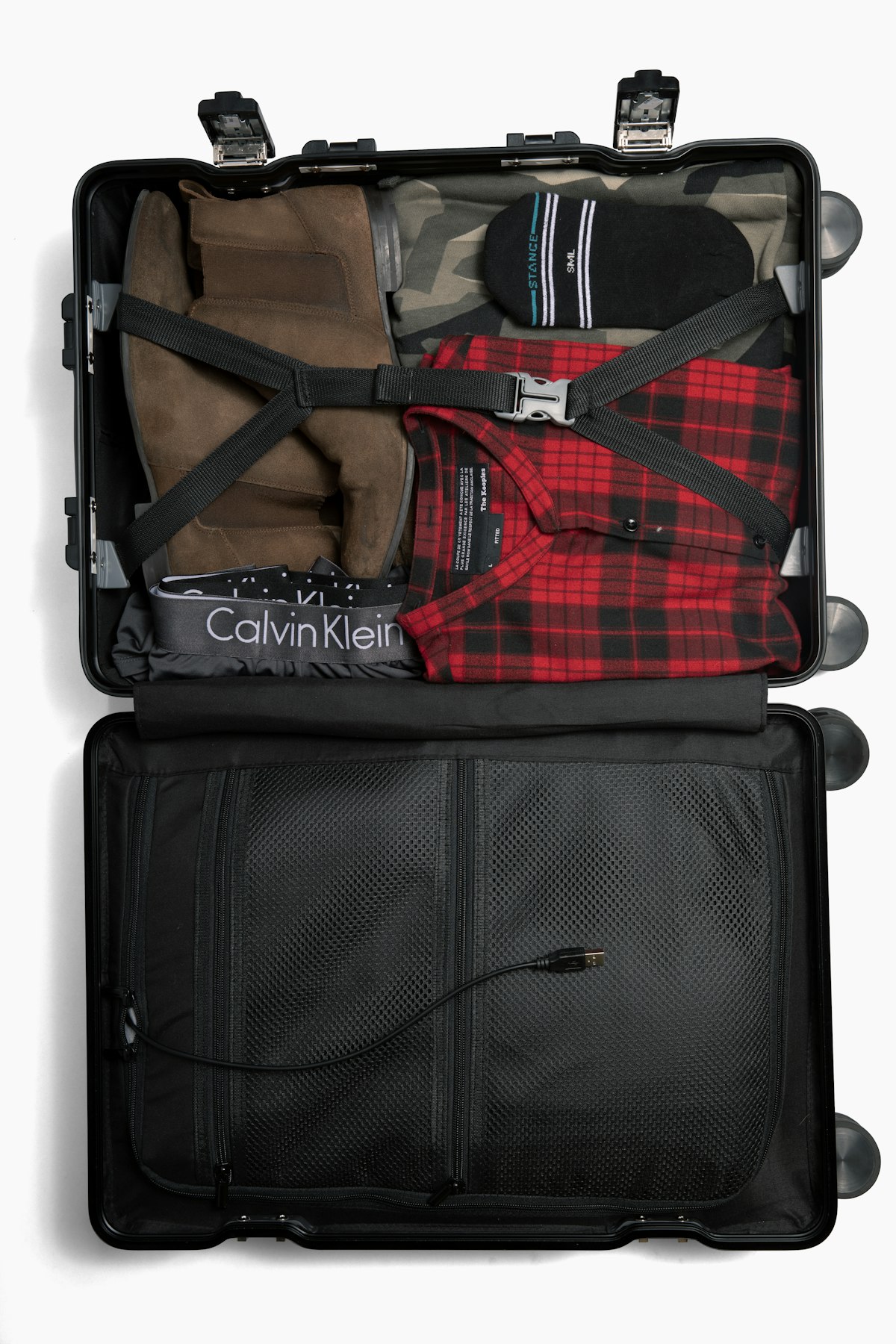 Open suitcase with neatly organized and strapped clothes ready for travel