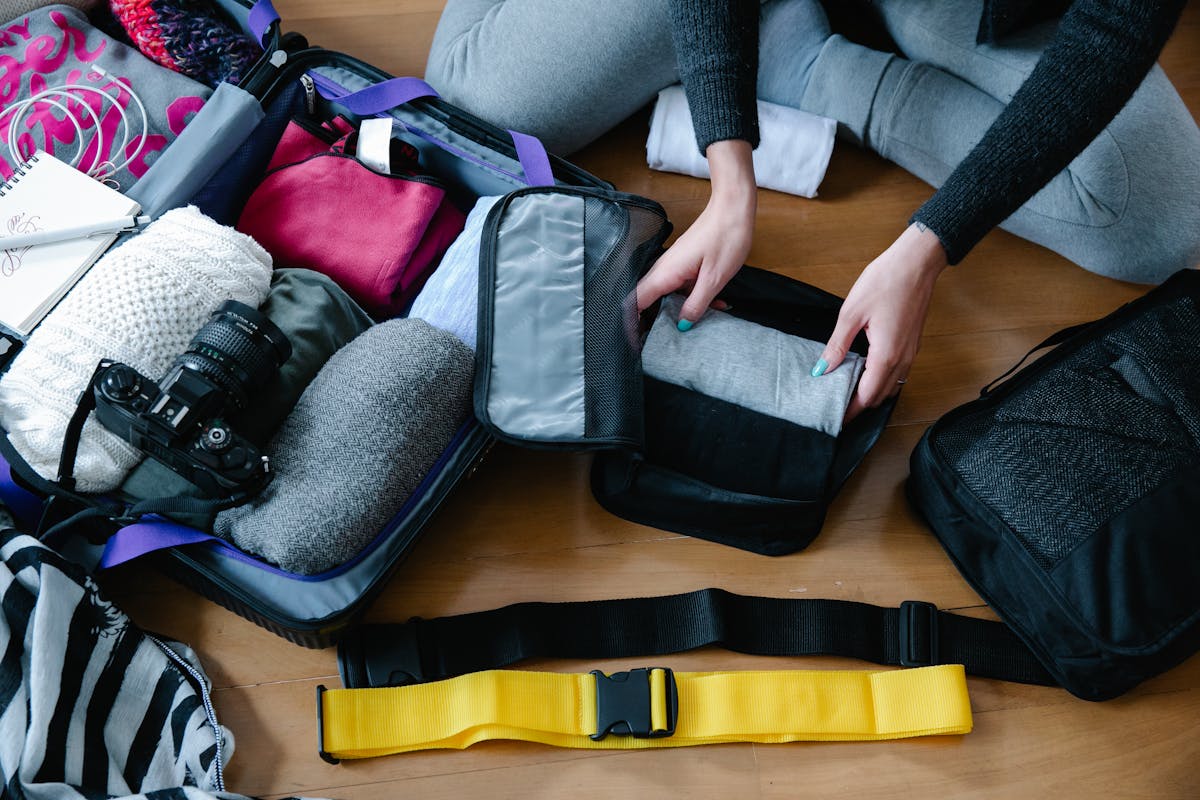Several packing cubes of different sizes organized on the floor next to a suitcase