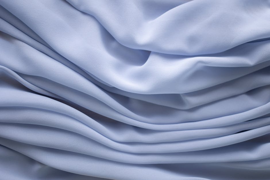 Close-up of smooth light blue wrinkle-free fabric with soft flowing folds showing how wrinkle-resistant materials look