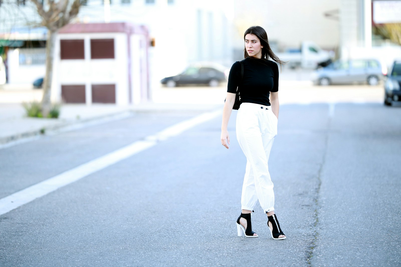 Woman walking in a fitted black top and white wide-leg pants demonstrating how contrast between fitted and loose clothing creates a focal point