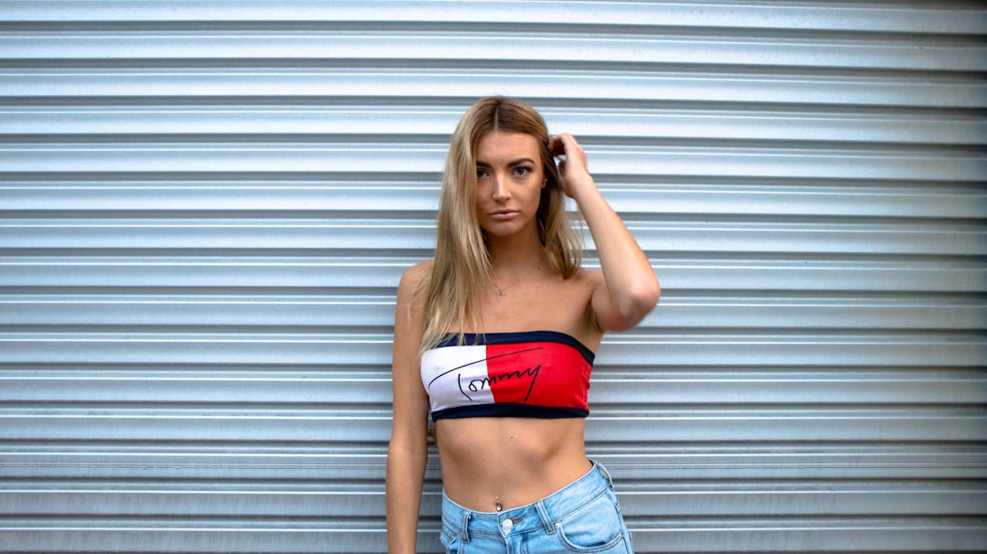 Woman wearing a strapless tube top standing against a corrugated metal wall showing the type of garment that relies on friction and compression to stay in place